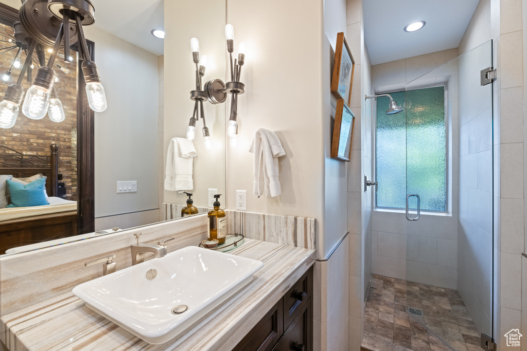 Bathroom with vanity, an enclosed shower, and tile walls