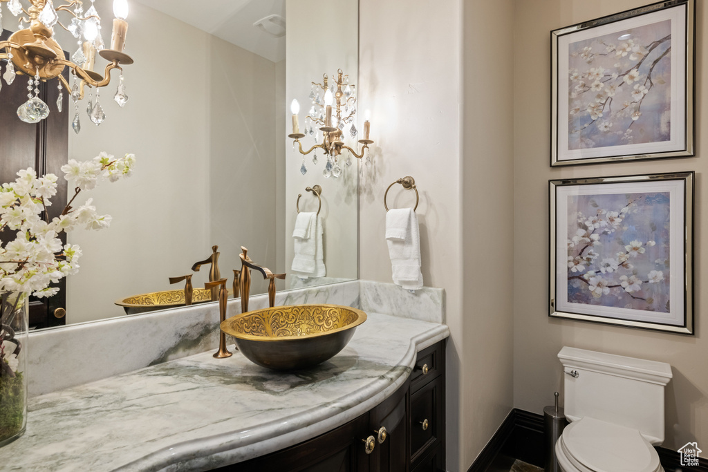 Bathroom with vanity, an inviting chandelier, and toilet