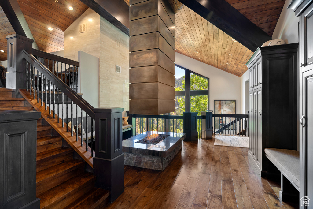 Stairway featuring dark hardwood / wood-style floors, beam ceiling, high vaulted ceiling, and wood ceiling