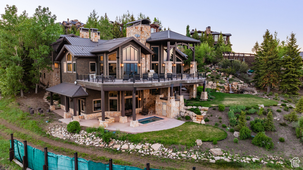 Rear view of house featuring a patio area and an in ground hot tub