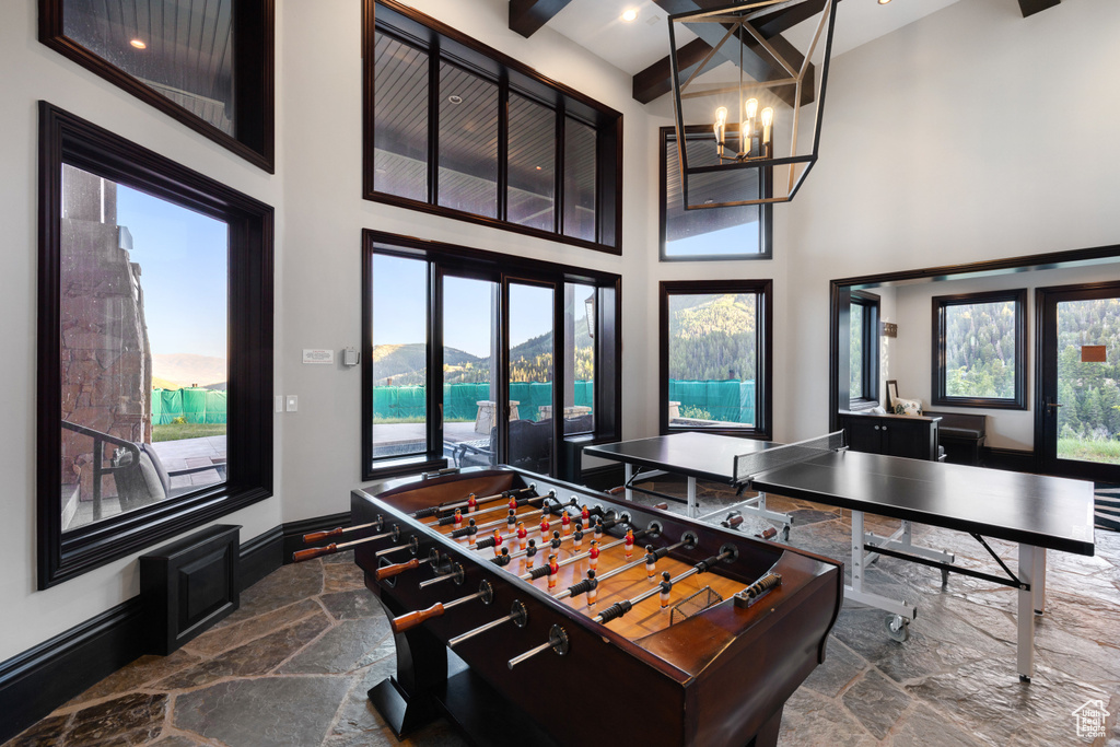 Playroom with a notable chandelier, a water view, plenty of natural light, and a towering ceiling