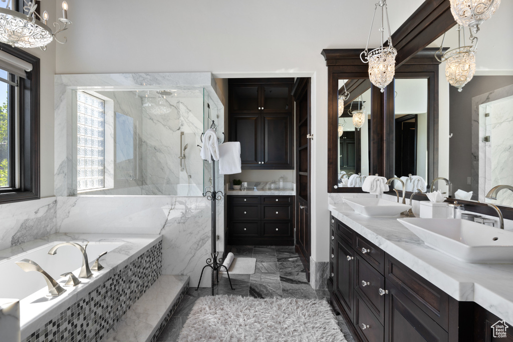 Bathroom featuring shower with separate bathtub, tile patterned floors, double sink vanity, and a chandelier