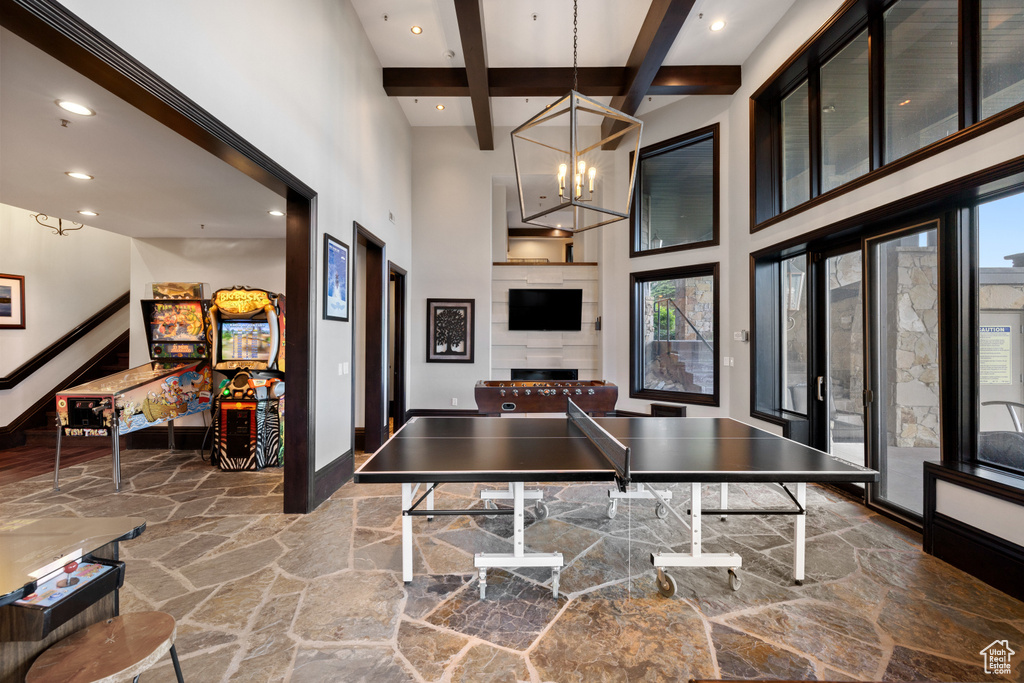 Game room featuring beamed ceiling, a notable chandelier, and a high ceiling