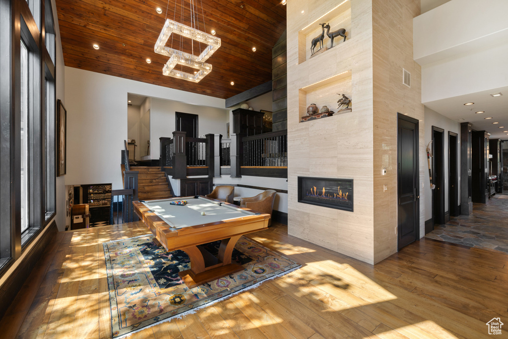 Rec room with a fireplace, wood-type flooring, billiards, a towering ceiling, and wood ceiling