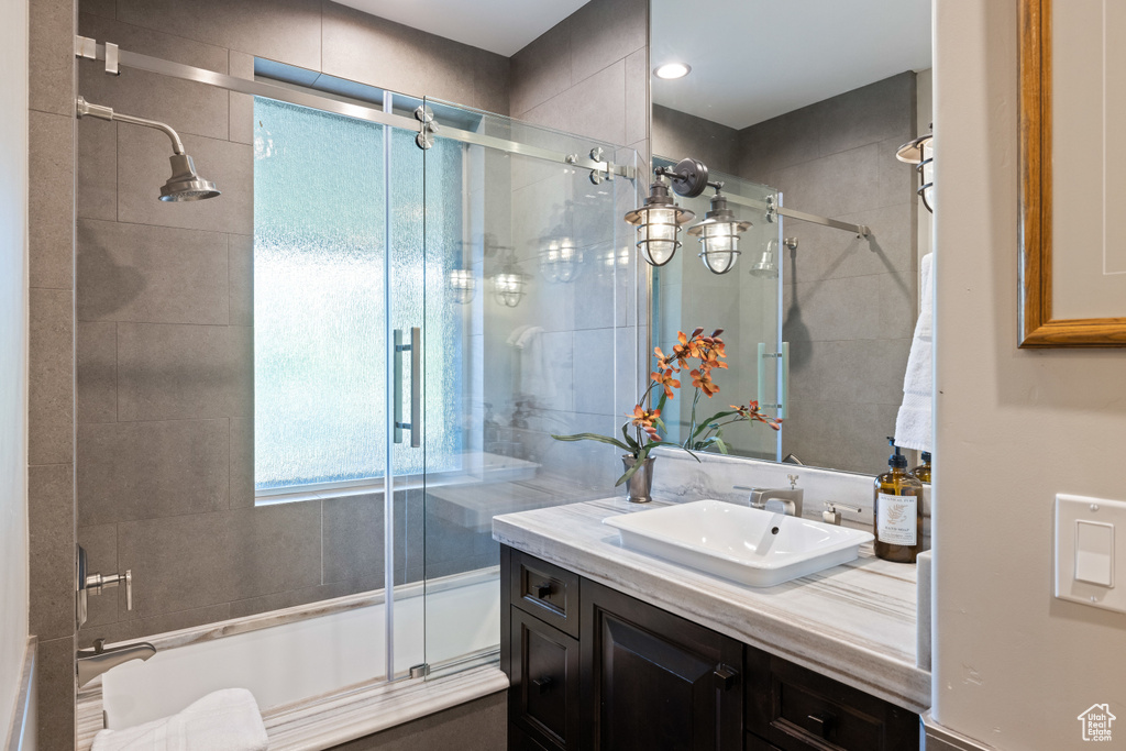 Bathroom with vanity and bath / shower combo with glass door