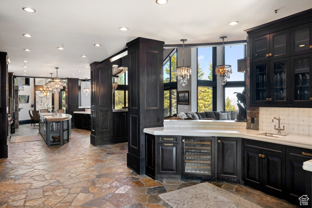 Kitchen with decorative backsplash, pendant lighting, sink, an inviting chandelier, and wine cooler