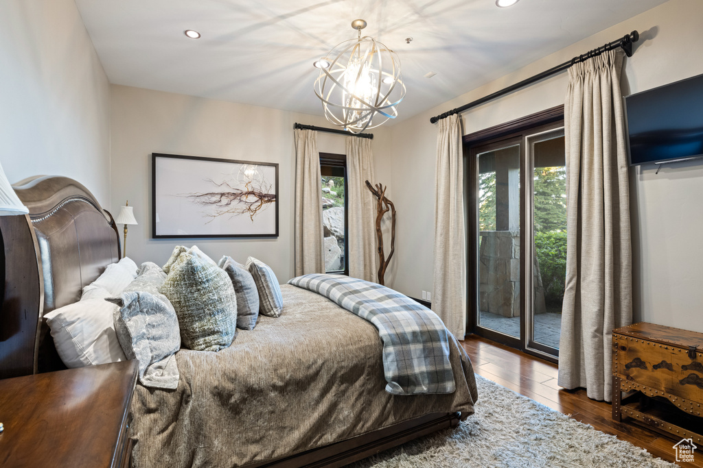 Bedroom featuring wood-type flooring, a notable chandelier, and access to exterior