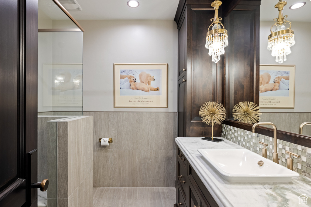 Bathroom with vanity, decorative backsplash, and tile walls