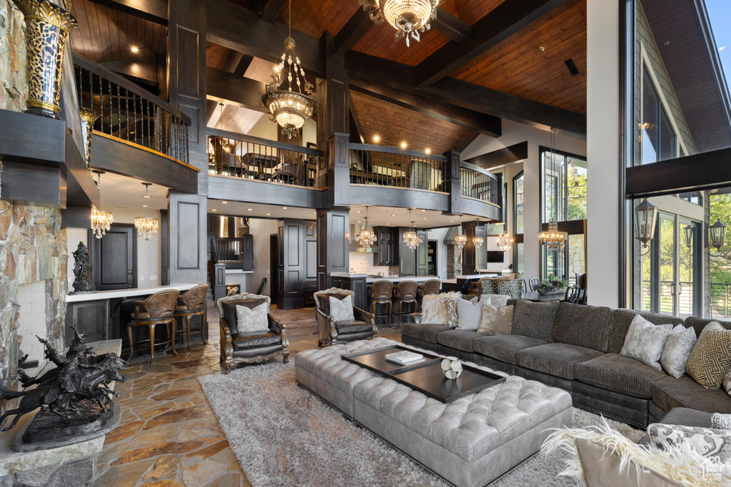 Living room with beam ceiling, a towering ceiling, a notable chandelier, and wooden ceiling