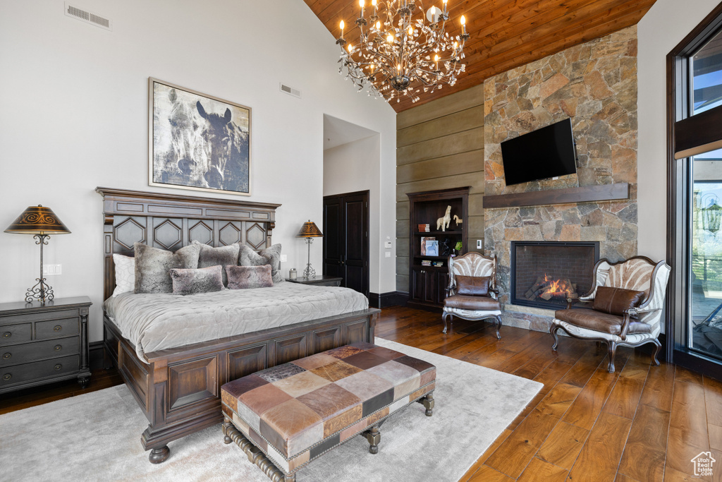 Bedroom featuring a fireplace, wood-type flooring, a chandelier, and high vaulted ceiling