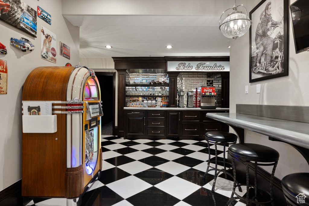 Bar featuring light tile patterned flooring, pendant lighting, and dark brown cabinets