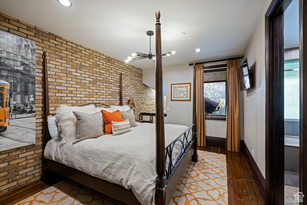 Bedroom featuring wood-type flooring and brick wall