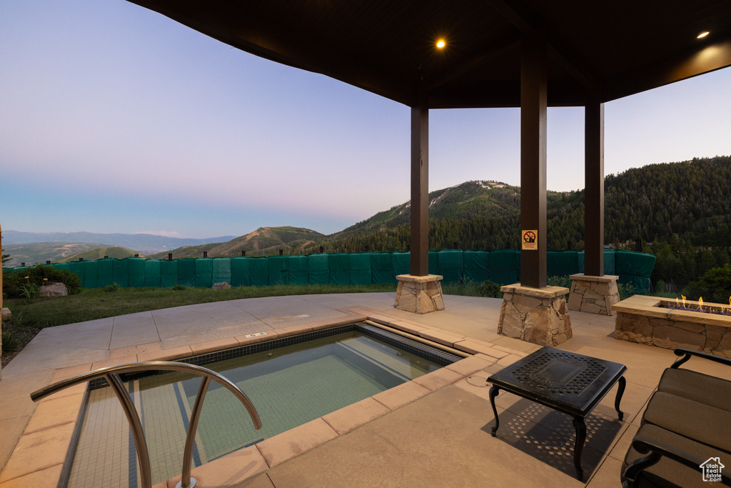 Pool at dusk featuring a mountain view and a patio