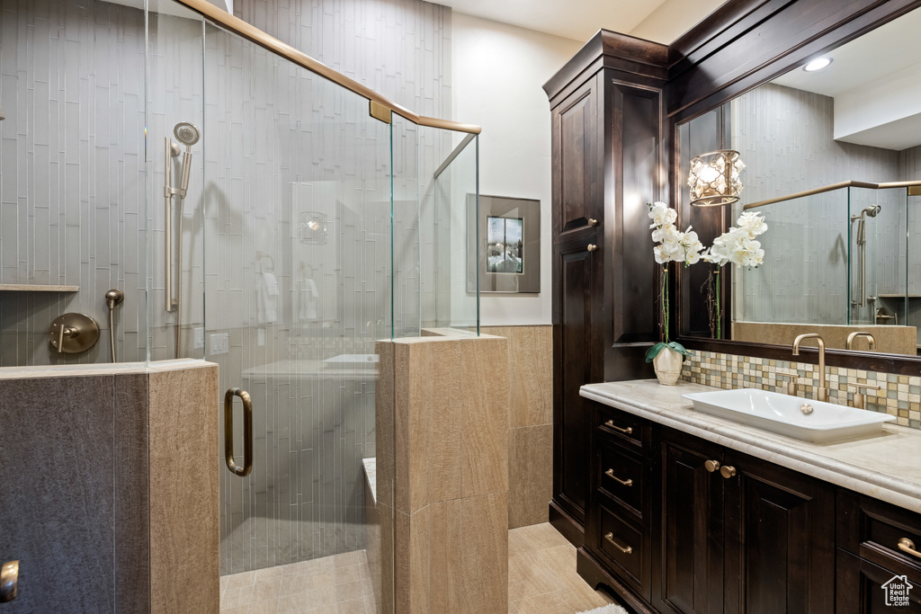 Bathroom featuring decorative backsplash, walk in shower, and vanity