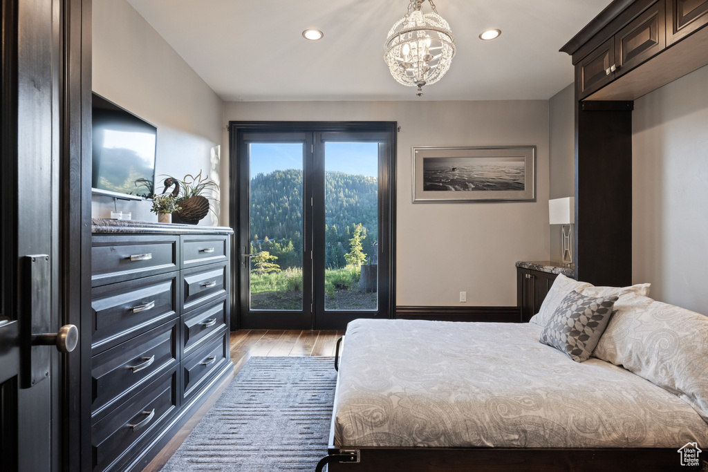 Bedroom featuring an inviting chandelier, multiple windows, wood-type flooring, and french doors