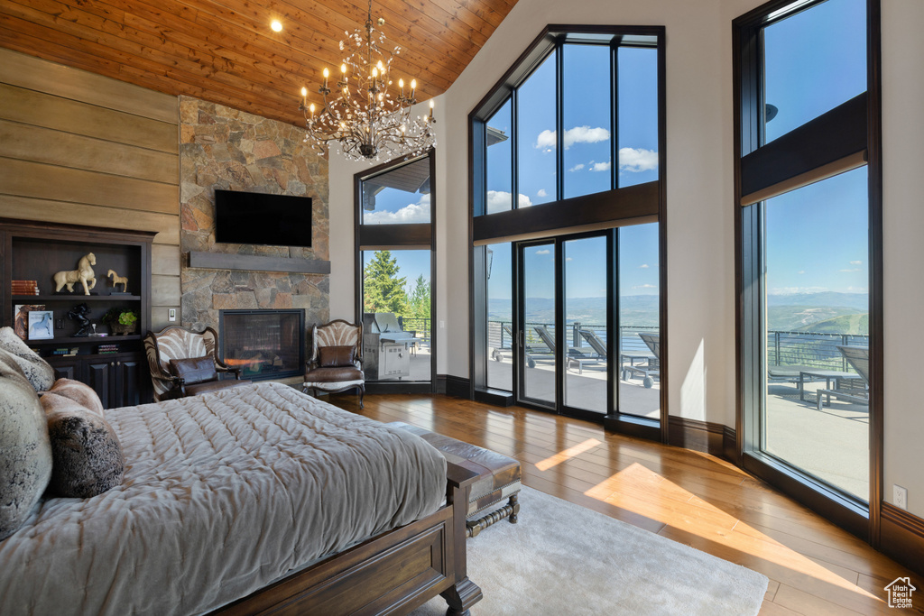 Bedroom featuring a fireplace, light hardwood / wood-style flooring, wood ceiling, and multiple windows