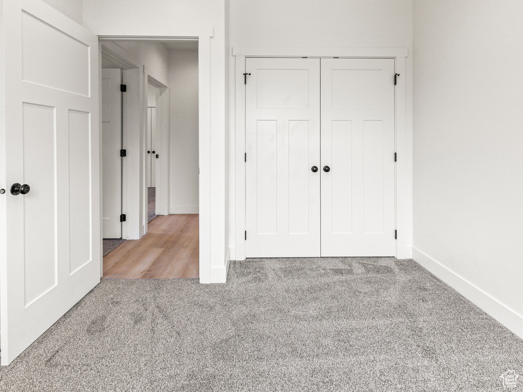 Unfurnished bedroom with light carpet and a closet