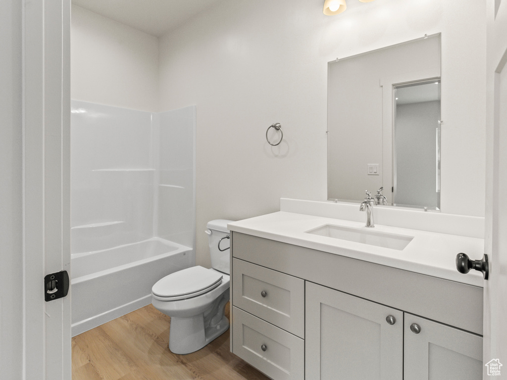 Full bathroom with tub / shower combination, vanity, toilet, and hardwood / wood-style floors