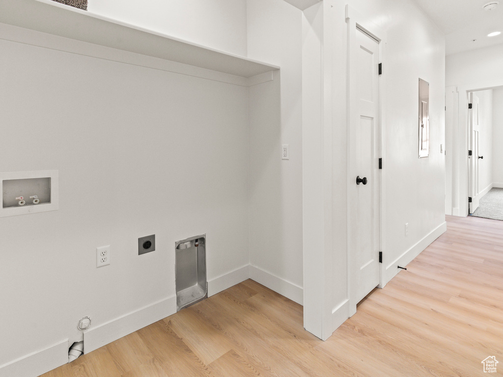 Clothes washing area with light hardwood / wood-style flooring, hookup for a washing machine, and electric dryer hookup