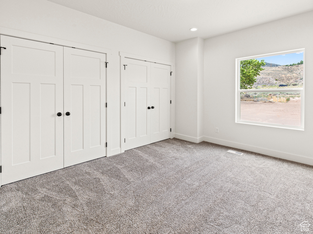 Unfurnished bedroom featuring light carpet and two closets