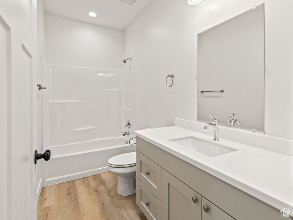 Full bathroom with shower / tub combination, vanity, toilet, and hardwood / wood-style floors