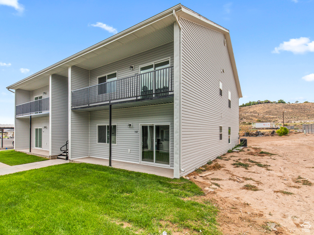 Back of property featuring a balcony and a yard