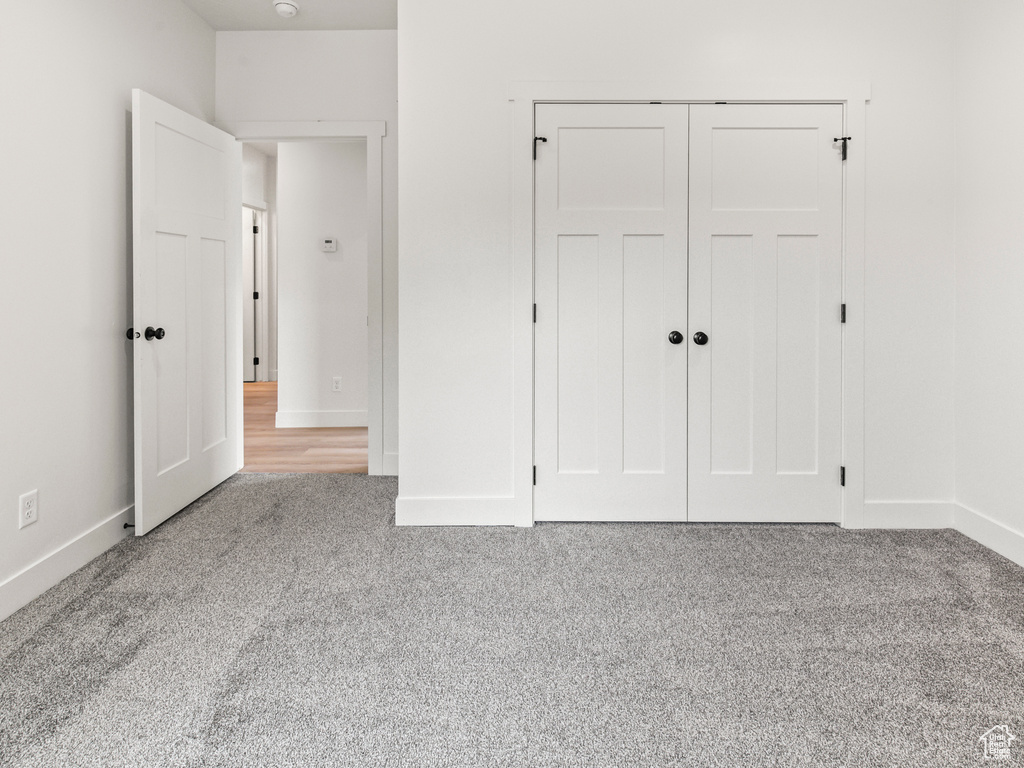 Unfurnished bedroom with light colored carpet and a closet