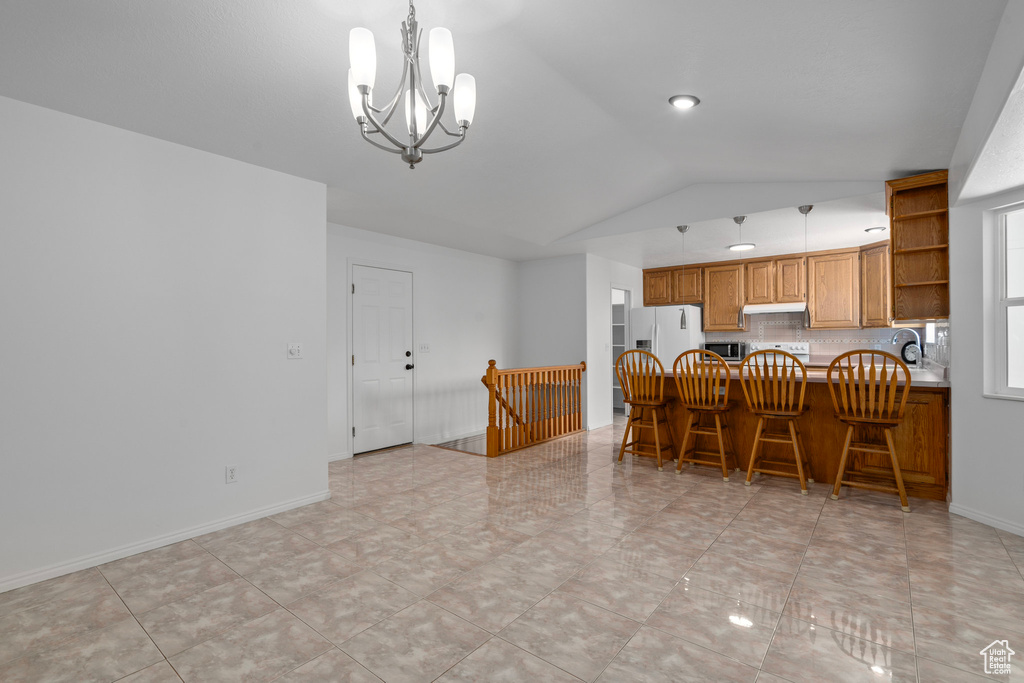 Kitchen featuring pendant lighting, lofted ceiling, white appliances, a notable chandelier, and light tile patterned flooring