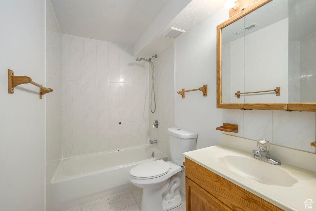 Full bathroom with vanity, tiled shower / bath combo, toilet, and tile patterned flooring