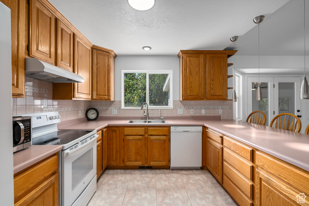 Kitchen featuring tasteful backsplash, light tile patterned floors, sink, decorative light fixtures, and white appliances