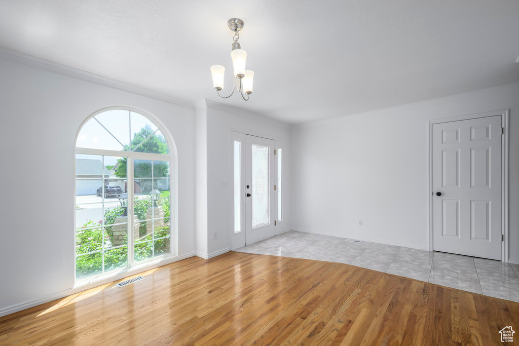 Foyer entrance with a notable chandelier, light wood-type flooring, and plenty of natural light