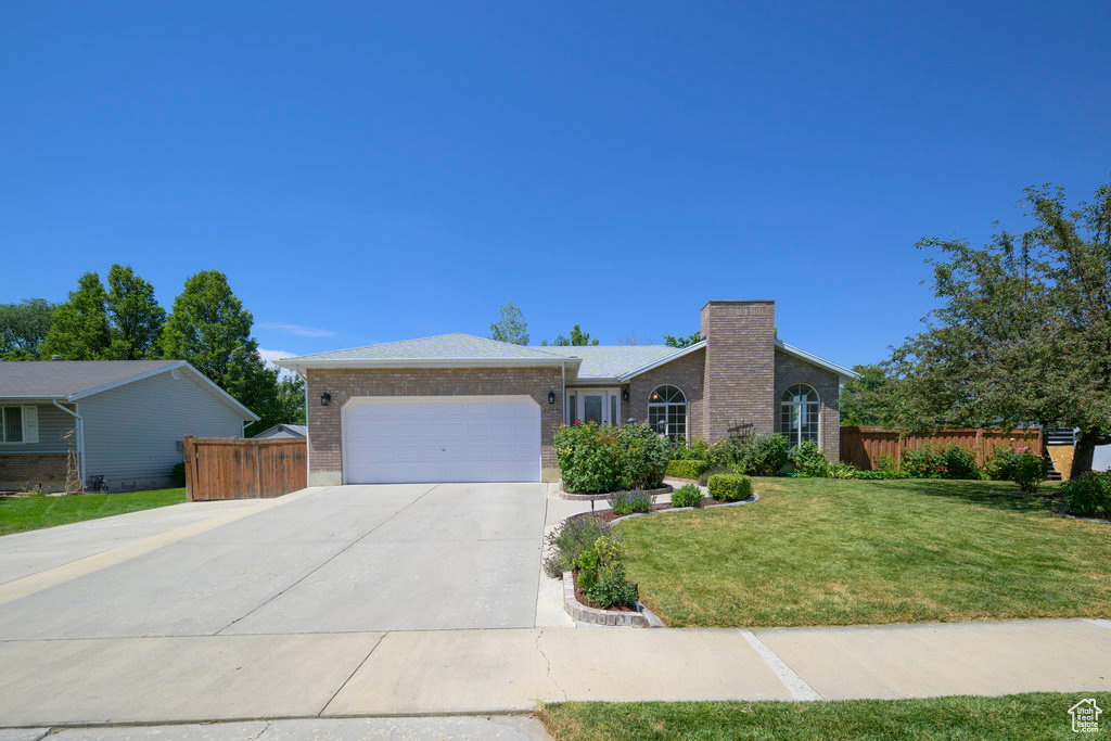 Ranch-style house featuring a garage and a front yard