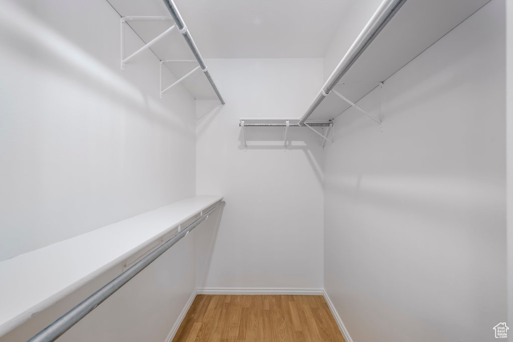 Walk in closet with light hardwood / wood-style flooring