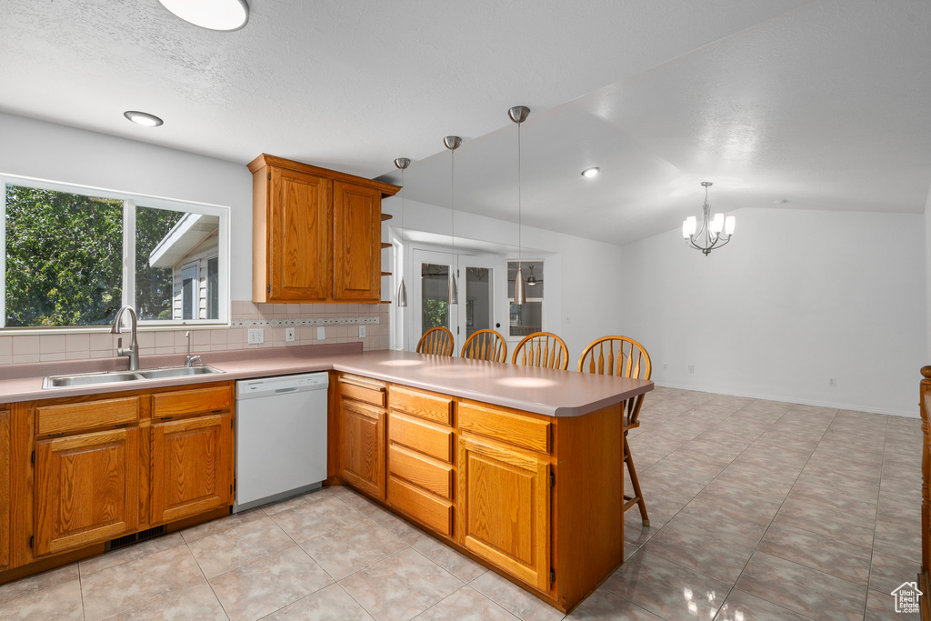 Kitchen with decorative backsplash, sink, white dishwasher, vaulted ceiling, and light tile patterned flooring