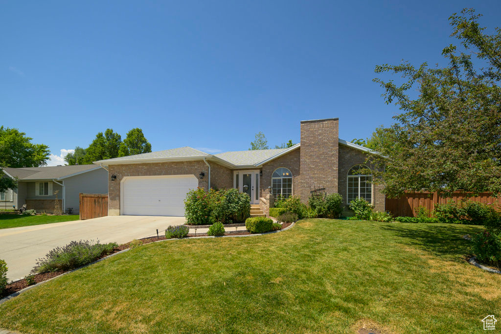 Ranch-style house featuring a garage and a front yard