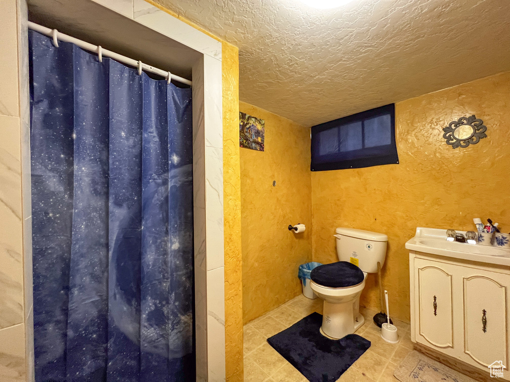 Bathroom featuring tile patterned flooring, toilet, vanity, and a textured ceiling