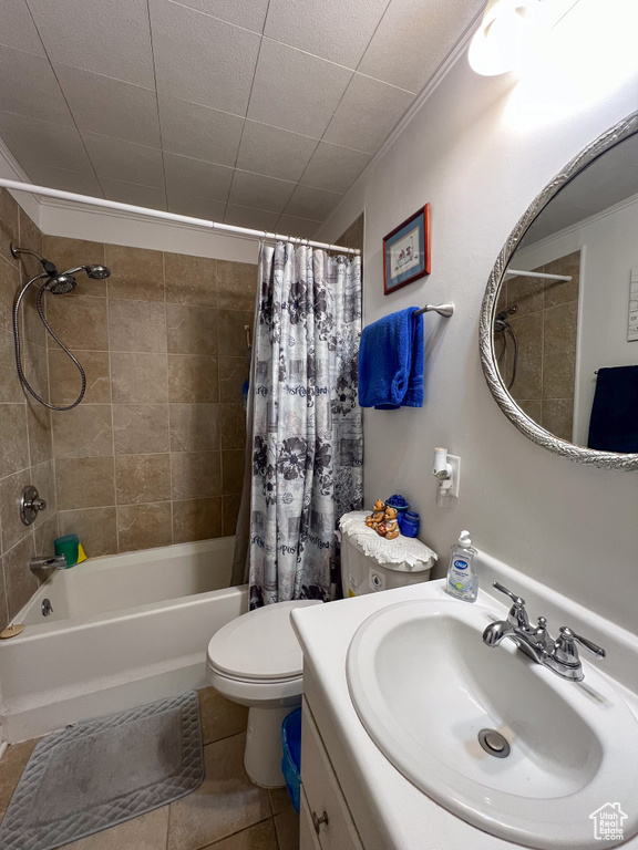 Full bathroom with tile patterned floors, toilet, vanity, and shower / tub combo with curtain