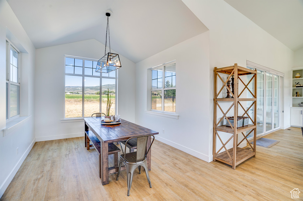 Dining area with a notable chandelier, high vaulted ceiling, and light wood-type flooring