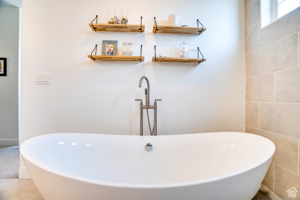 Bathroom with a washtub, tile patterned flooring, and tile walls