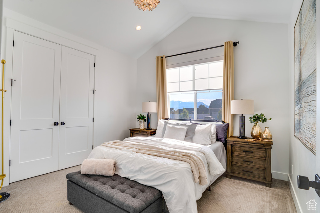 Bedroom featuring a closet, light colored carpet, and vaulted ceiling