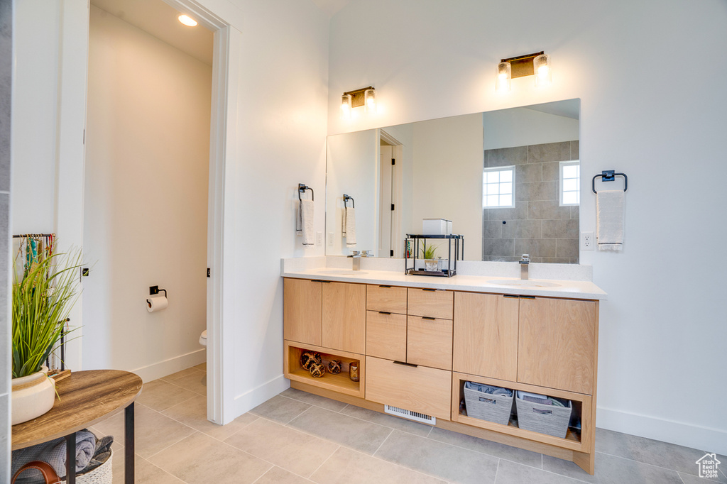 Bathroom featuring toilet, tile patterned flooring, and double vanity