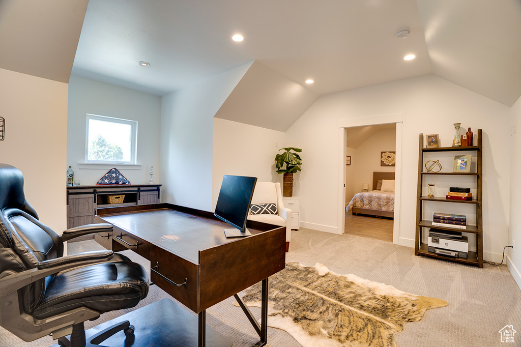 Home office with vaulted ceiling and light colored carpet