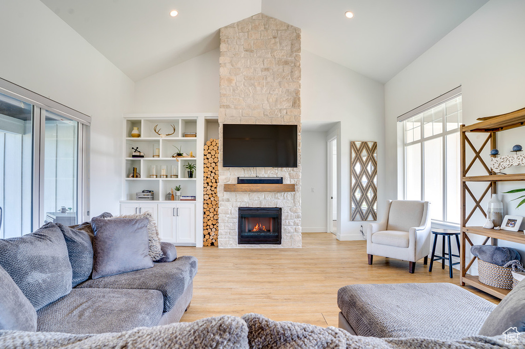 Living room with high vaulted ceiling, a fireplace, and light hardwood / wood-style floors