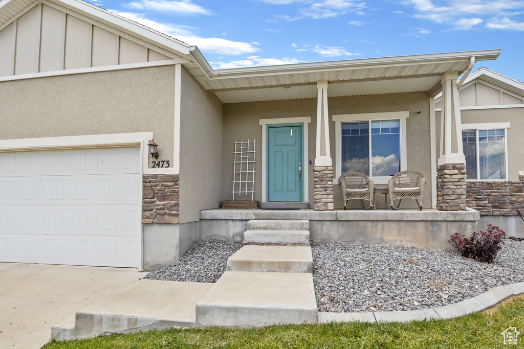 Entrance to property featuring a garage and covered porch