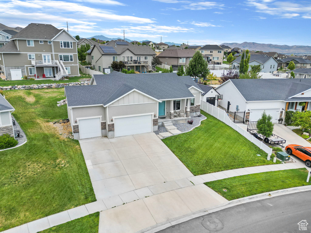 View of front of home with a mountain view, a garage, and a front lawn