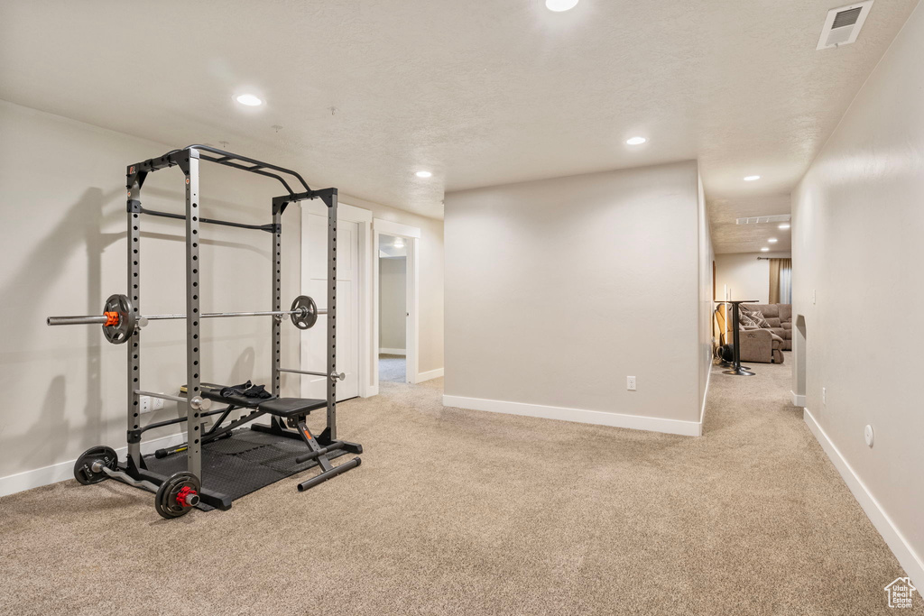 Exercise area with a textured ceiling and light colored carpet