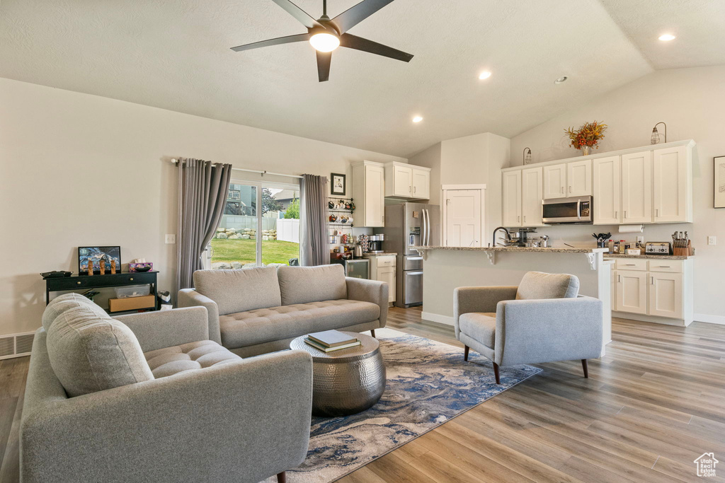 Living room featuring light hardwood / wood-style floors, sink, high vaulted ceiling, and ceiling fan