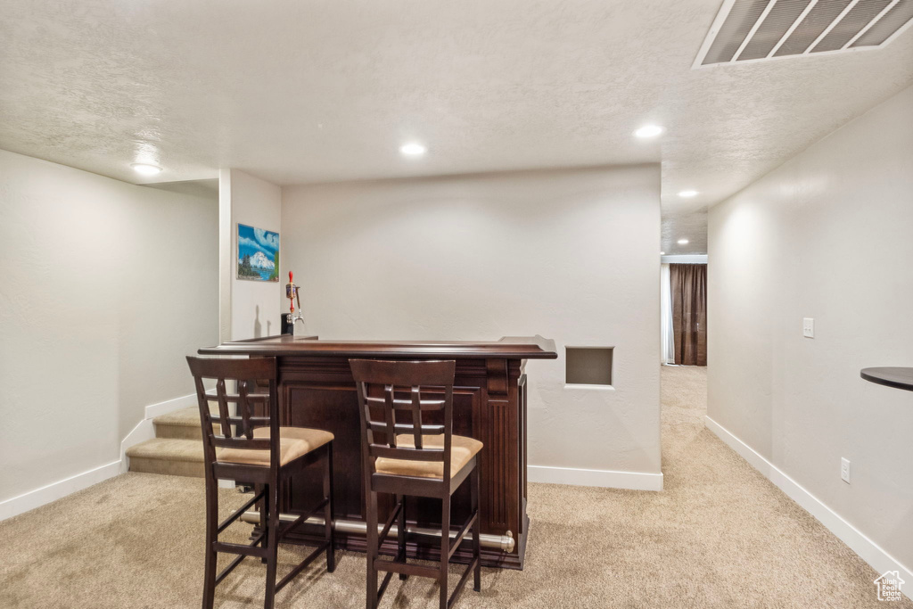 Bar featuring a textured ceiling and light colored carpet