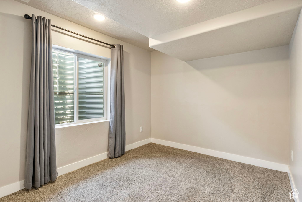 Carpeted spare room featuring a textured ceiling