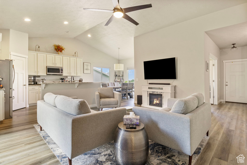 Living room featuring light hardwood / wood-style floors, high vaulted ceiling, and ceiling fan